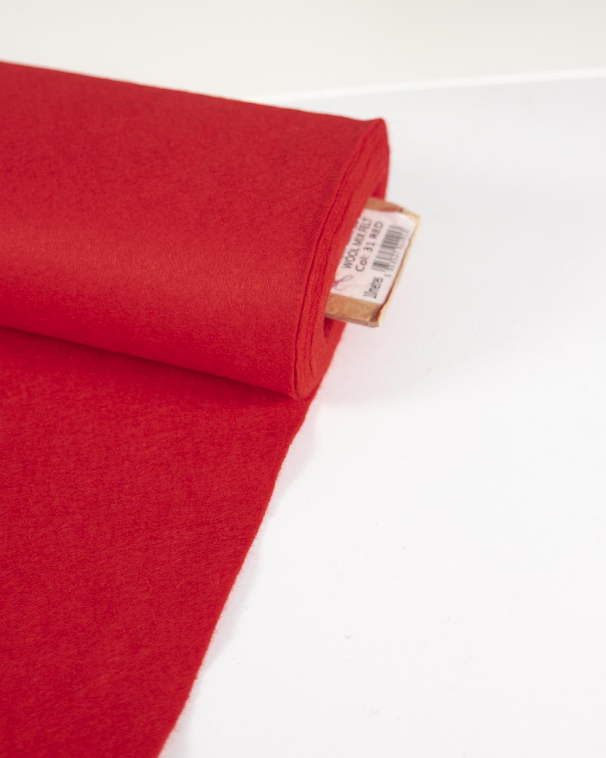 A roll of bright red wool and viscose felt fabric, partially unrolled on a clean white surface.