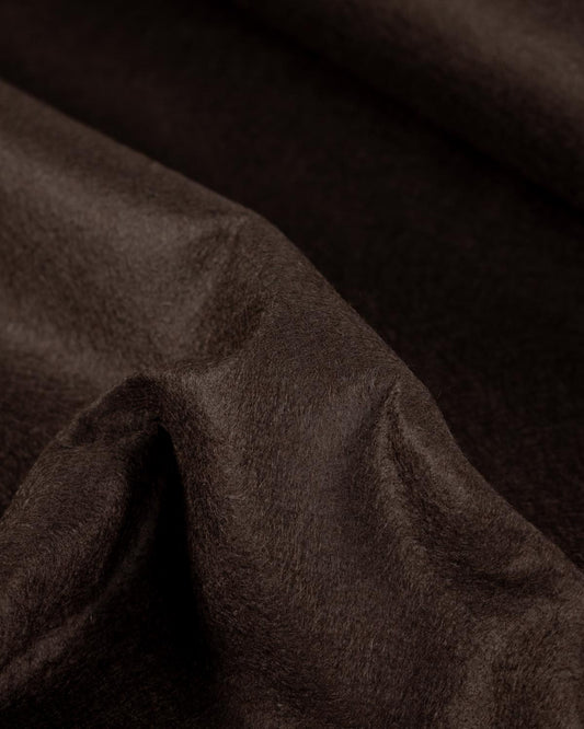 A close-up of draped dark brown textured wool and viscose felt fabric with soft folds, showing its textured surface.
