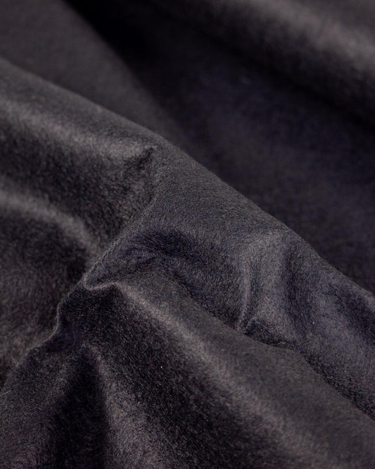 A close-up of draped black wool and viscose felt fabric with a soft, plush texture.