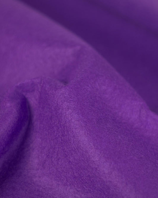 Purple wool and viscose felt fabric, gathered up to show its firm structure and textured surface.