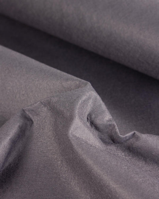 A close-up of draped grey wool and viscose felt fabric with a soft, slightly textured surface and folds.