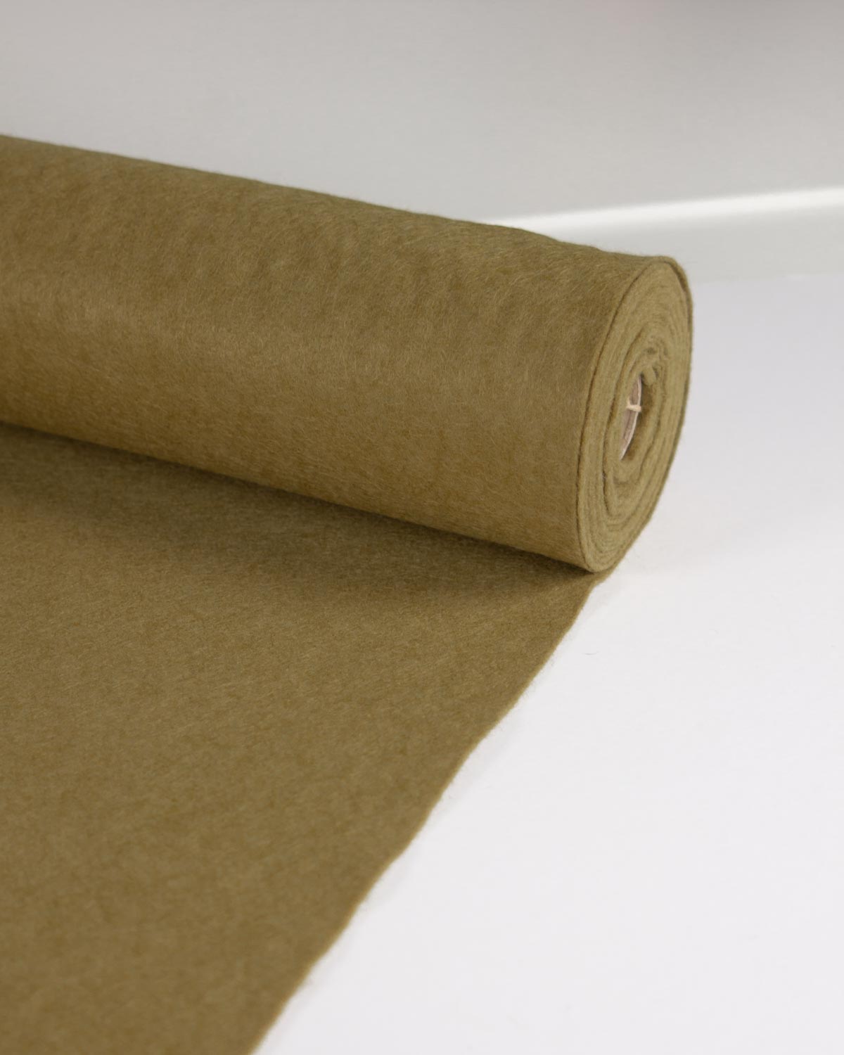 A roll of mustard olive wool and viscose felt fabric, partially unrolled on a clean white surface.
