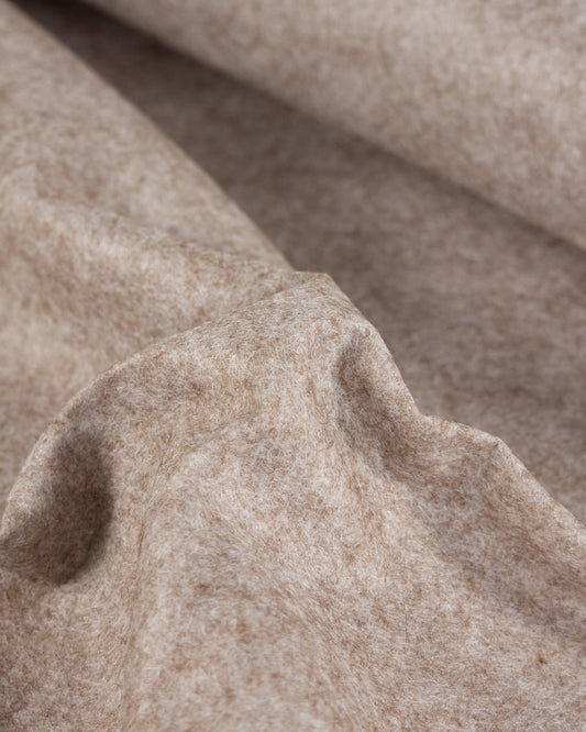 A close-up of draped fawn marl beige wool and viscose felt fabric with a soft, textured surface.