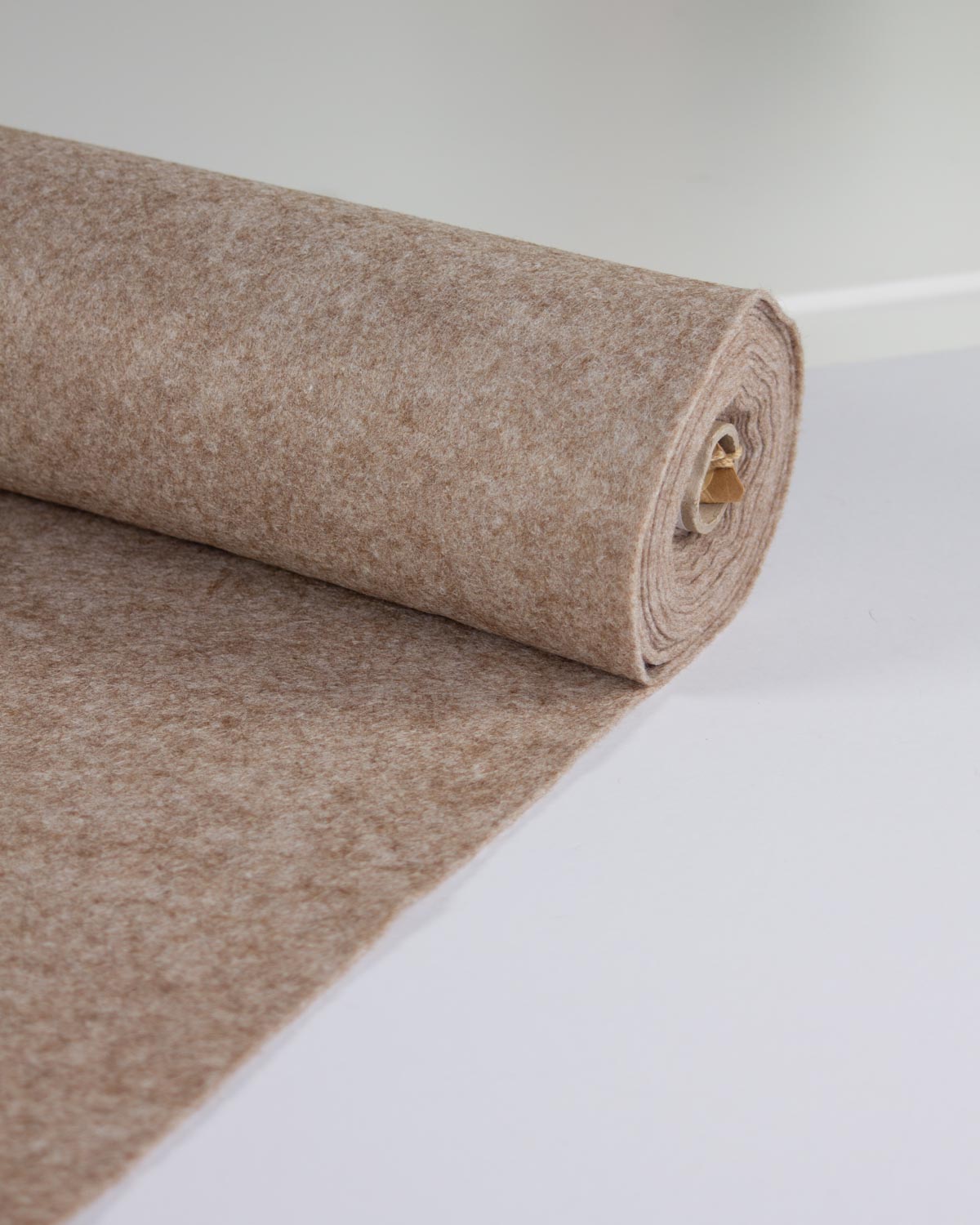 A roll of light brown fawn marl wool and viscose felt fabric, partially unrolled to show its textured surface, set against a clean white background.