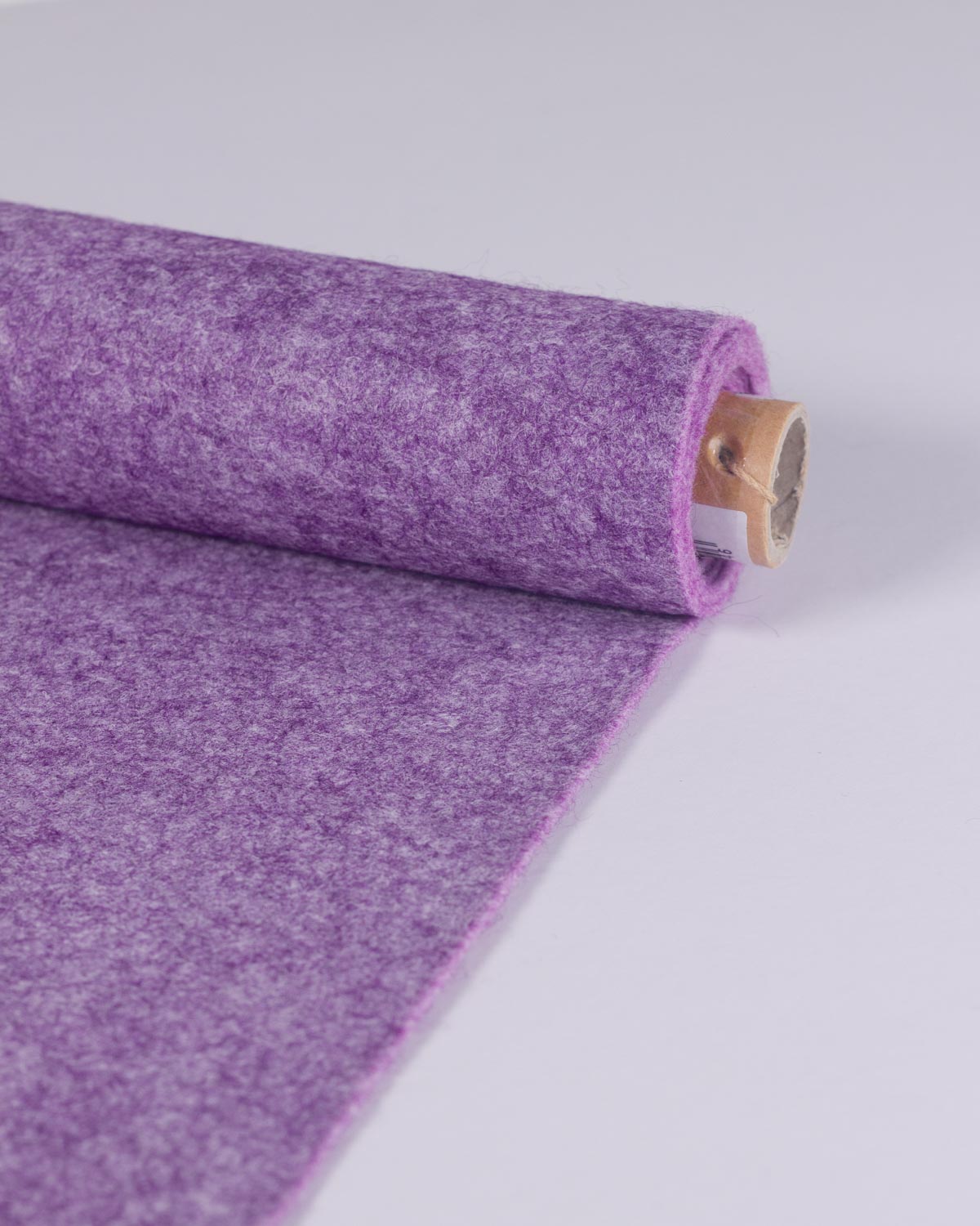 A roll of heather marl purple wool and viscose felt fabric partially unrolled, showing its textured surface and a light wood core, set against a plain light gray background.