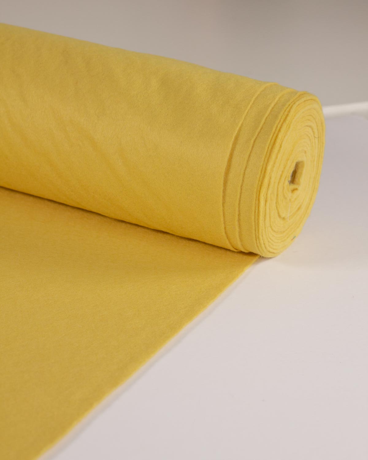 A roll of wool and viscose felt fabric rolled out onto a white surface.