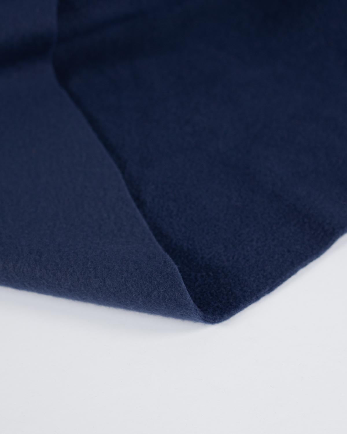A close-up of a folded navy blue fabric, showing its soft texture and smooth surface against a clean white background.