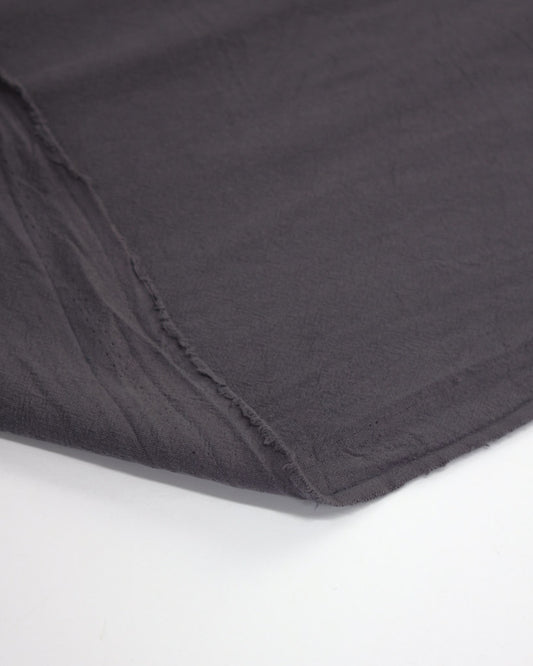 Flipped edge of crushed washed cotton fabric in dark grey