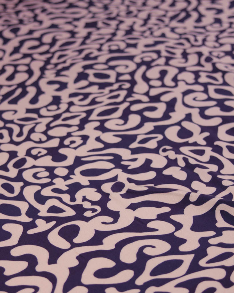 Abstract patterned viscose twill fabric with abstract designs on a purple background