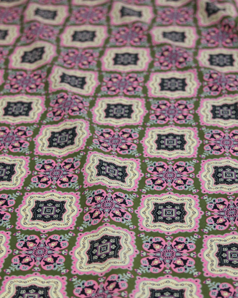 Patterned cotton lawn fabric with geometric design on a green background