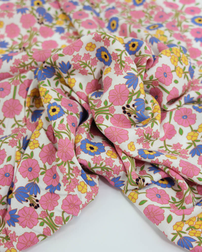 Floral viscose crepe fabric with pink, blue, and yellow flowers on a white background