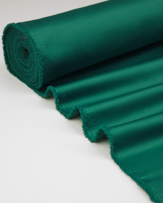 Roll of green duchess satin fabric on a white background