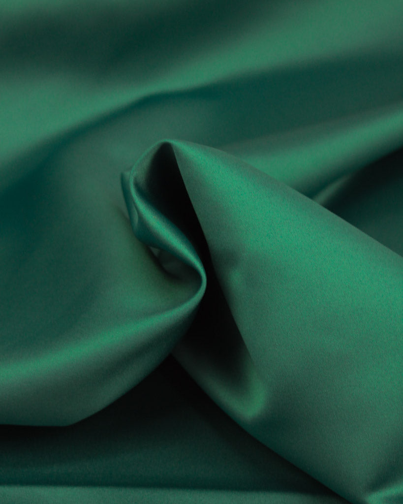 Close-up of green satin fabric with folds