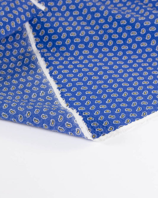 Close-up of huckleberry blue seersucker fabric showing an all-over tiny floral paisley design
