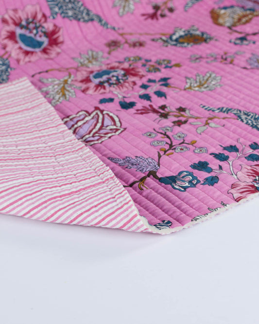 Close-up of a pink floral quilt fabric with a striped reverse on a white background