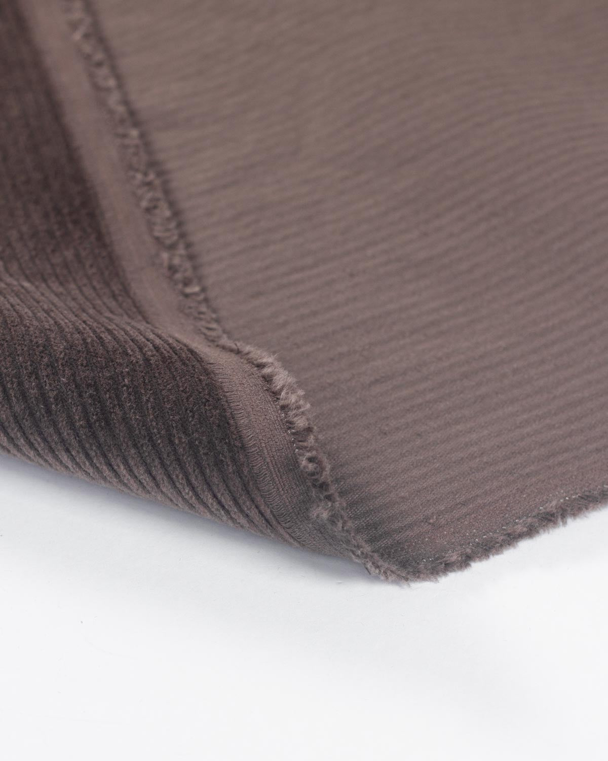 Close up of a cotton corduroy fabric in a brown shade showing the selvedge