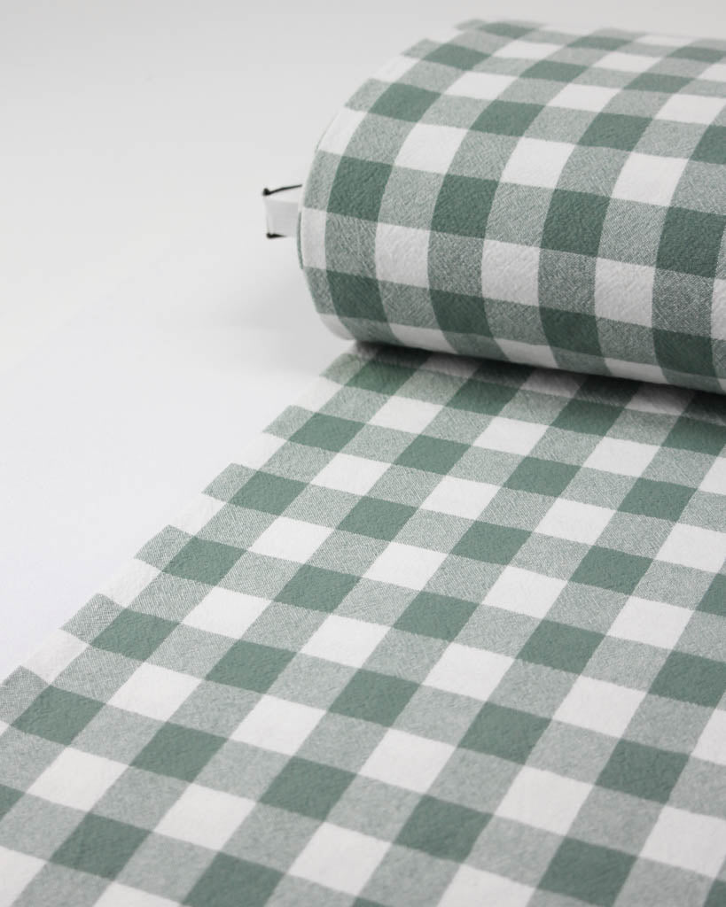 Roll of green and white checkered gingham fabric on a white background