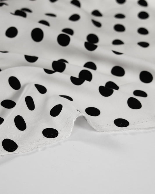 White viscose fabric with a black polka dot pattern.
