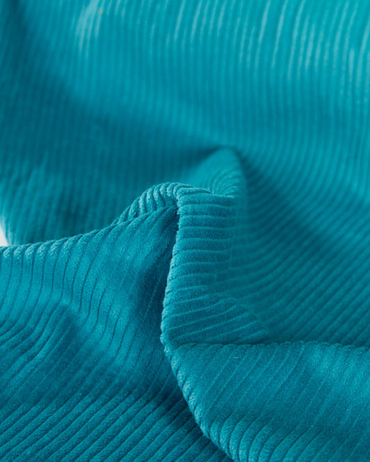 A close-up of teal cotton corduroy fabric with a ribbed texture and soft folds.