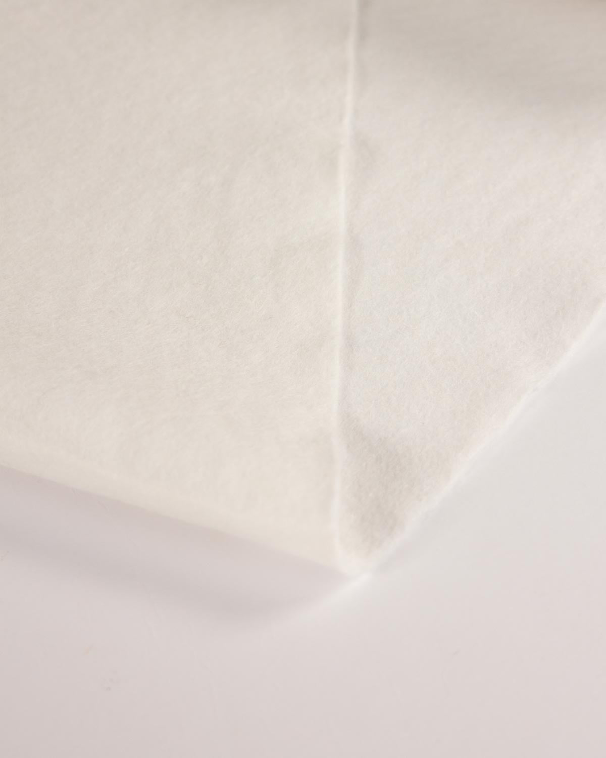 A close-up of a white wool and viscose felt fabric surface with a visible fold and soft texture on a plain light background.
