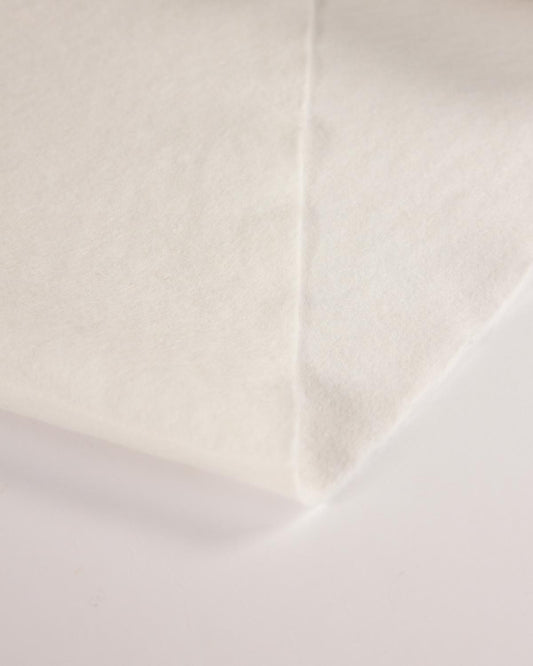 A close-up of a white wool and viscose felt fabric surface with a visible fold and soft texture on a plain light background.