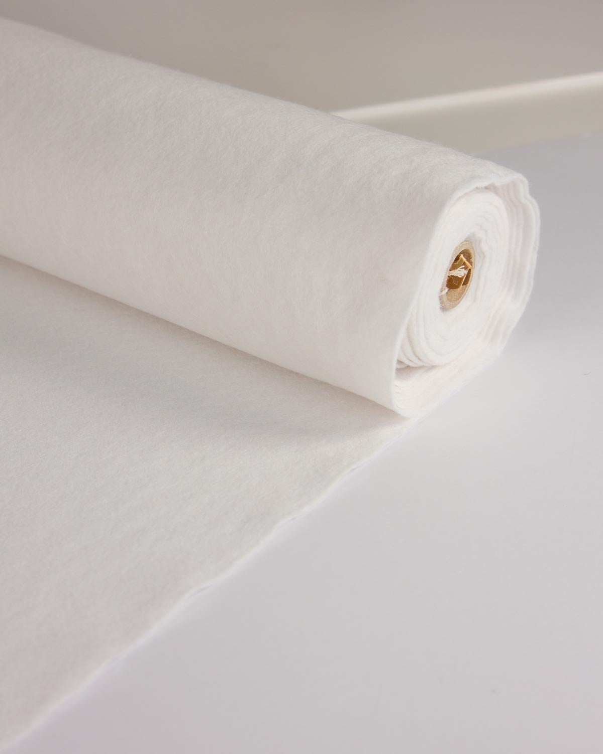 A roll of white wool and viscose felt fabric, shown partially unrolled on a clean white surface.