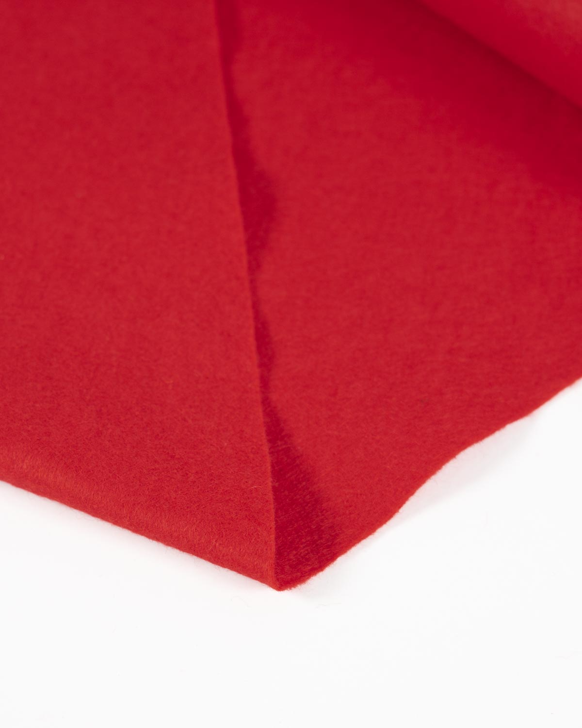 A piece of bright red wool and viscose felt folded on a white surface showing its bold colour and texture.