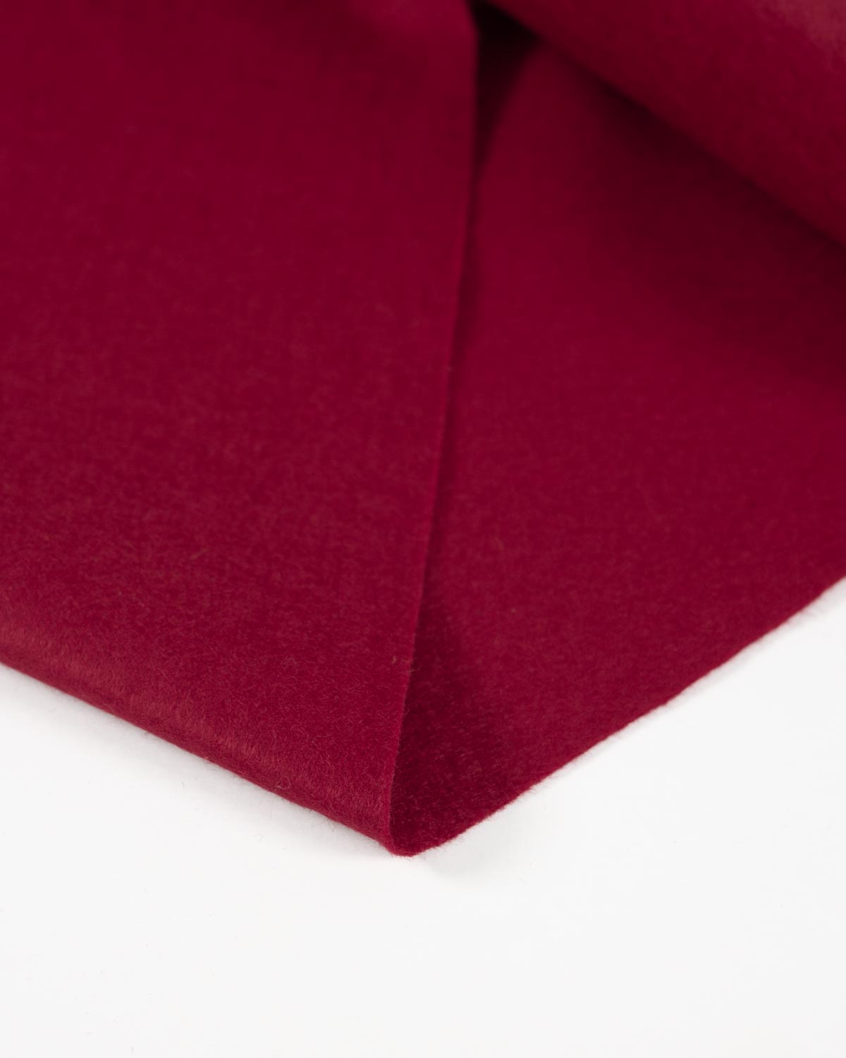 A piece of cherry red wool and viscose felt fabric folded on a plain white background, showing its bold colour and textured surface.