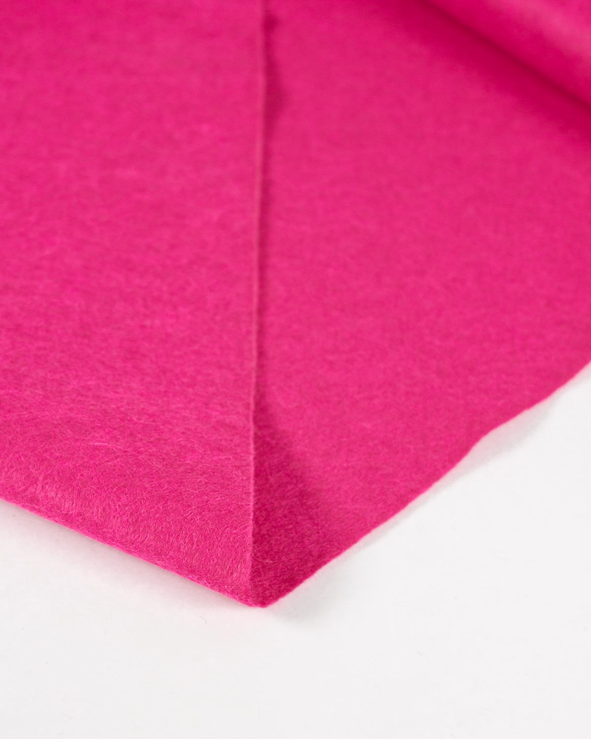 A piece of bright pink wool and viscose felt, folded on a white background to showcase its bold and even surface. 