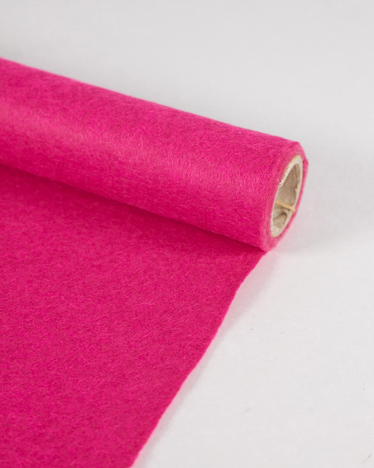 A roll of bright pink wool and viscose felt fabric, partially unrolled onto a plain white surface.