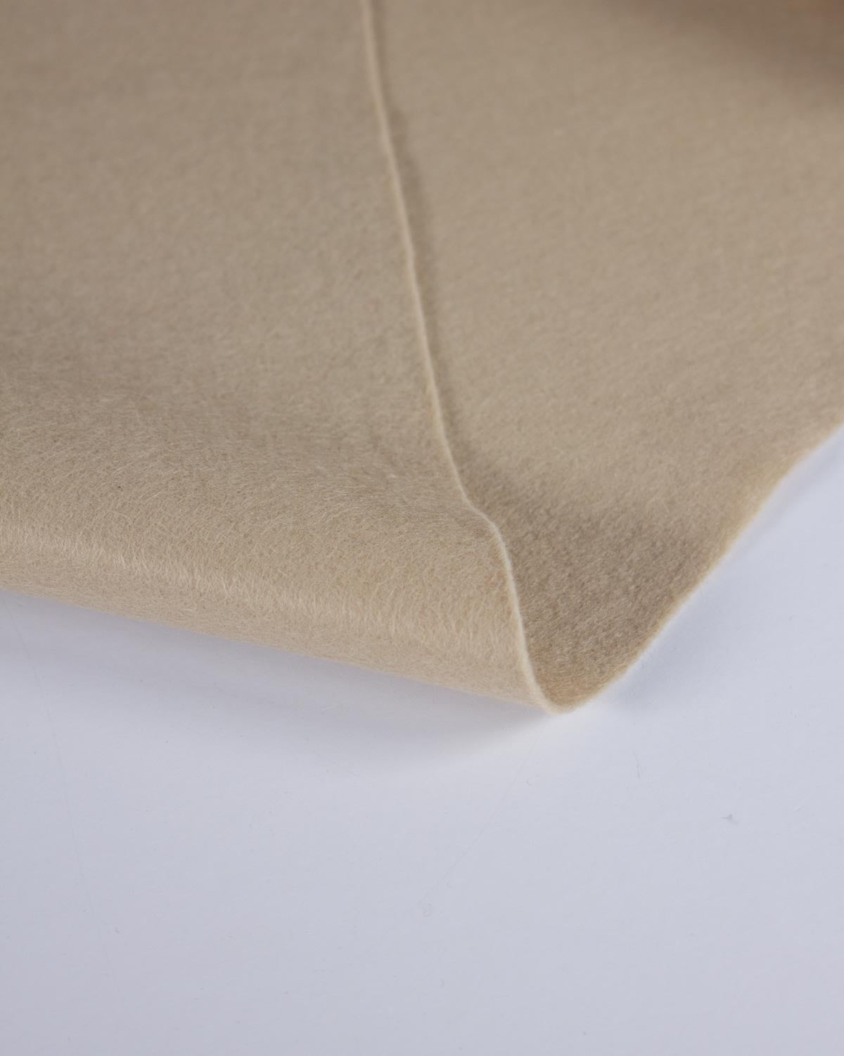 A close-up of a folded beige light stone wool and viscose fabric, showing its soft texture and smooth surface against a plain white background.