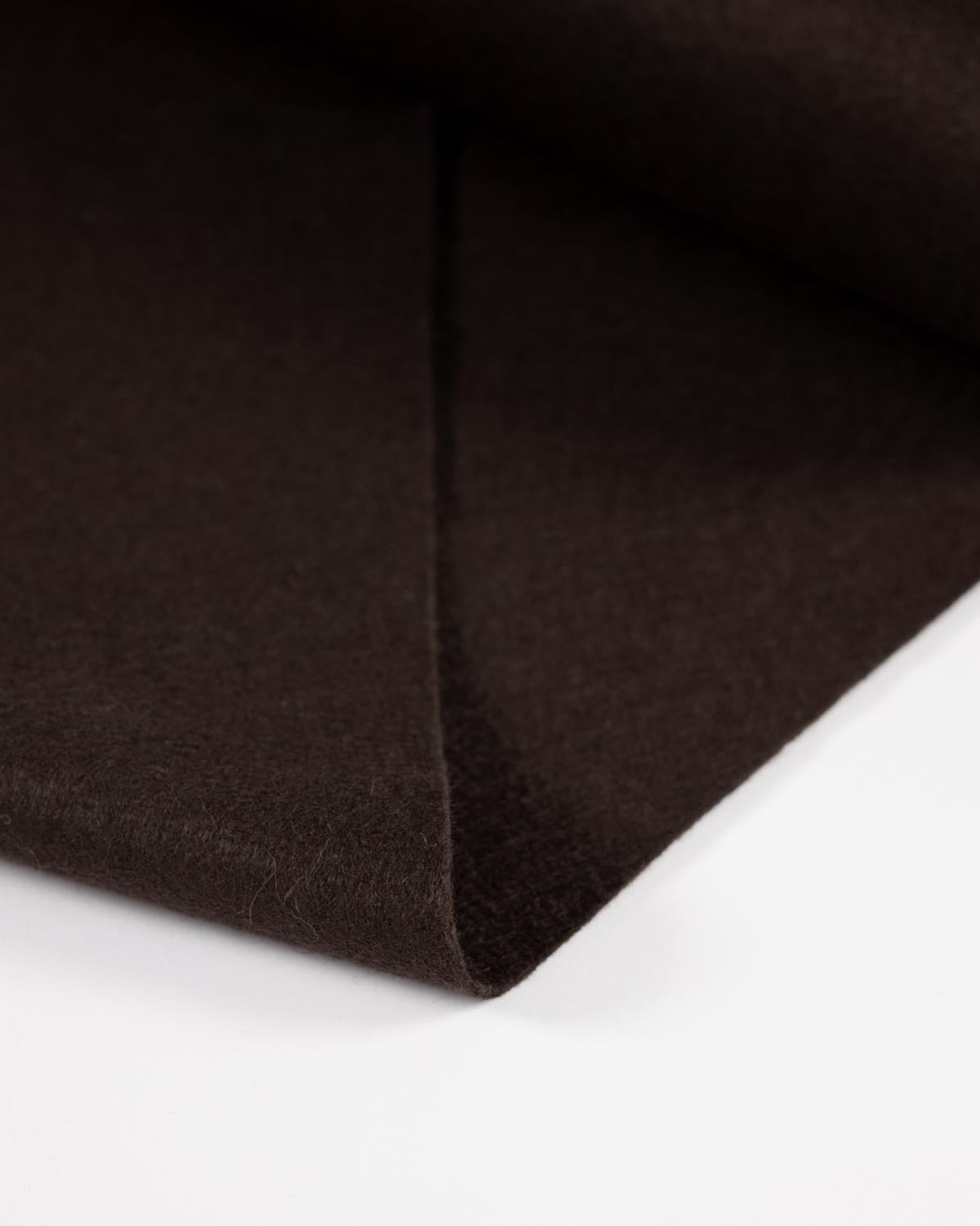 A close-up of dark brown wool and viscose felt fabric folded over on a white background, showing its soft, matte texture.