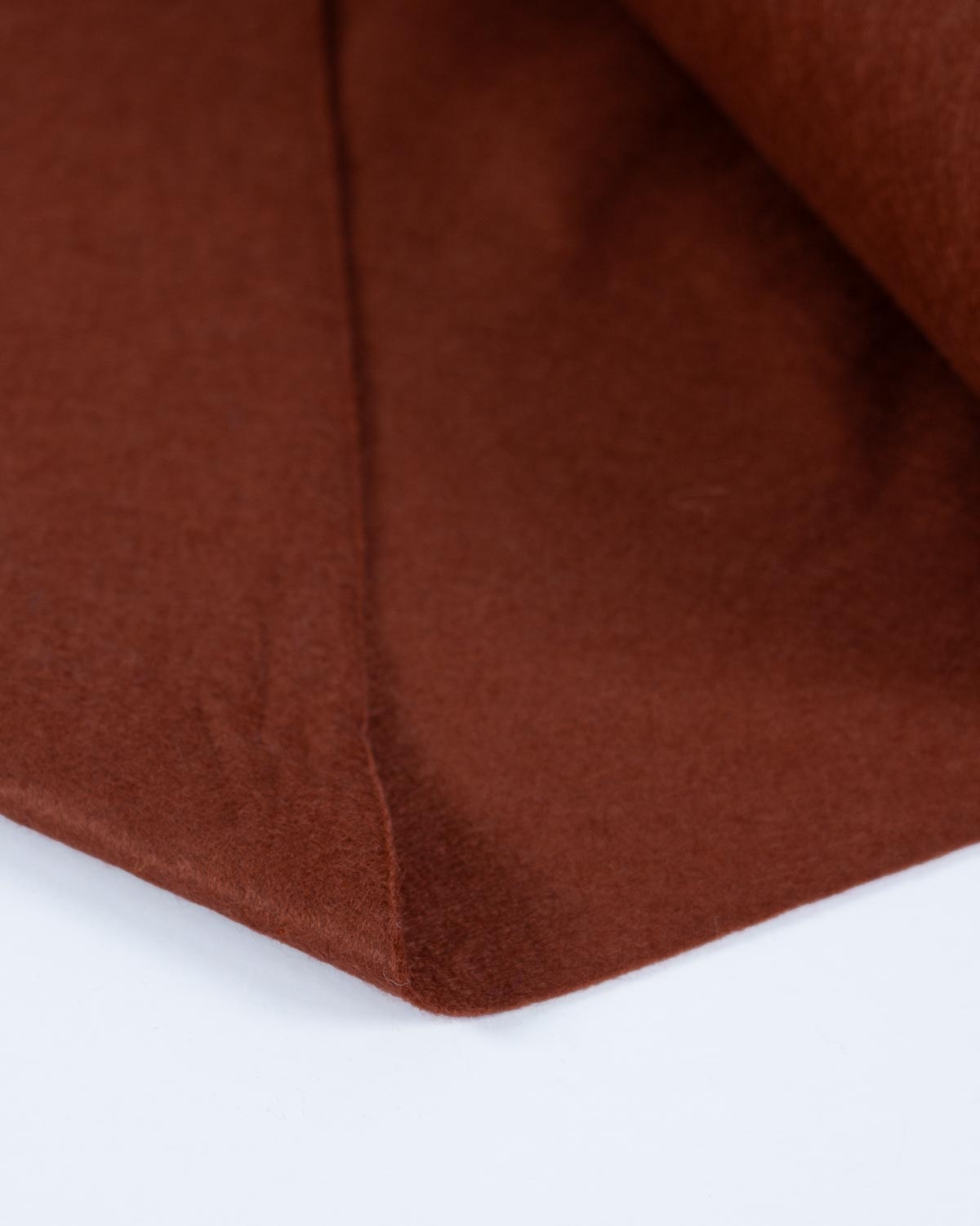 A piece of chestnut brown wool and viscose felt fabric, folded onto a white background, showing its texture and even, bold colour. 