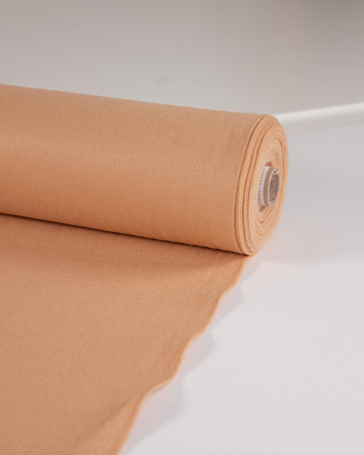 A roll of light beige wool and viscose felt fabric unrolled, set against a clean white background.