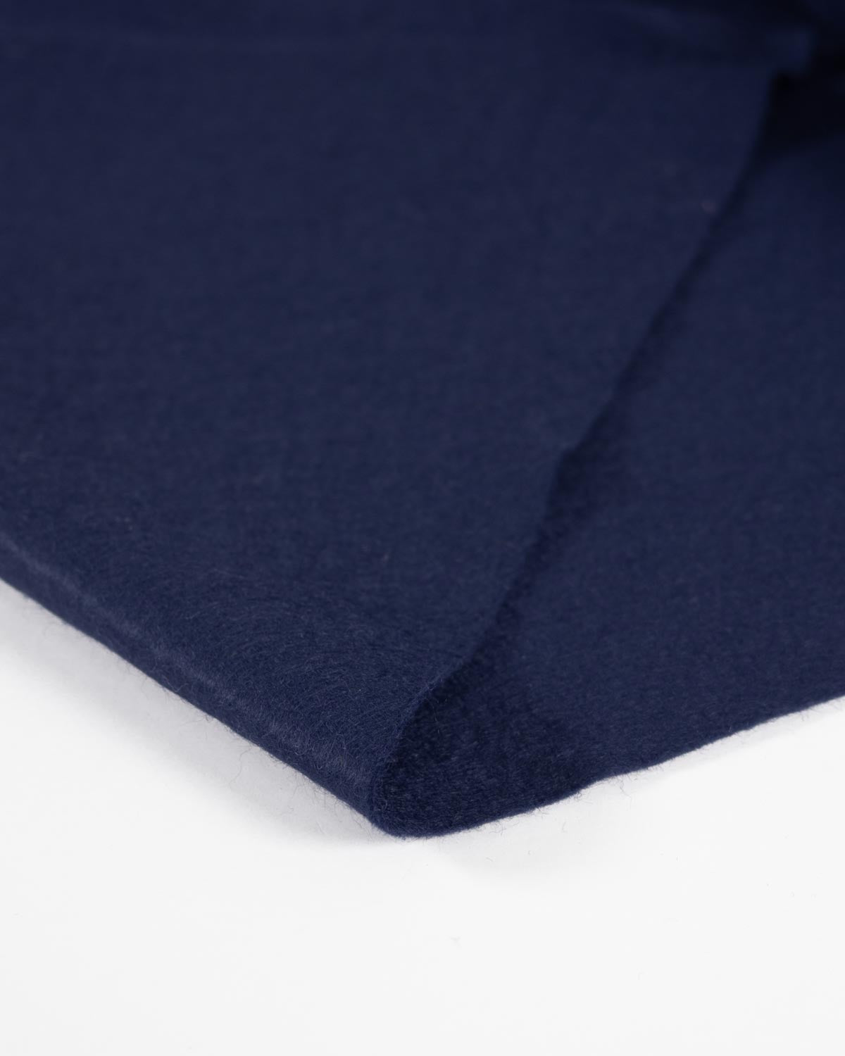 A close-up of folded navy blue wool and viscose felt fabric showing its soft texture against a clean white background.