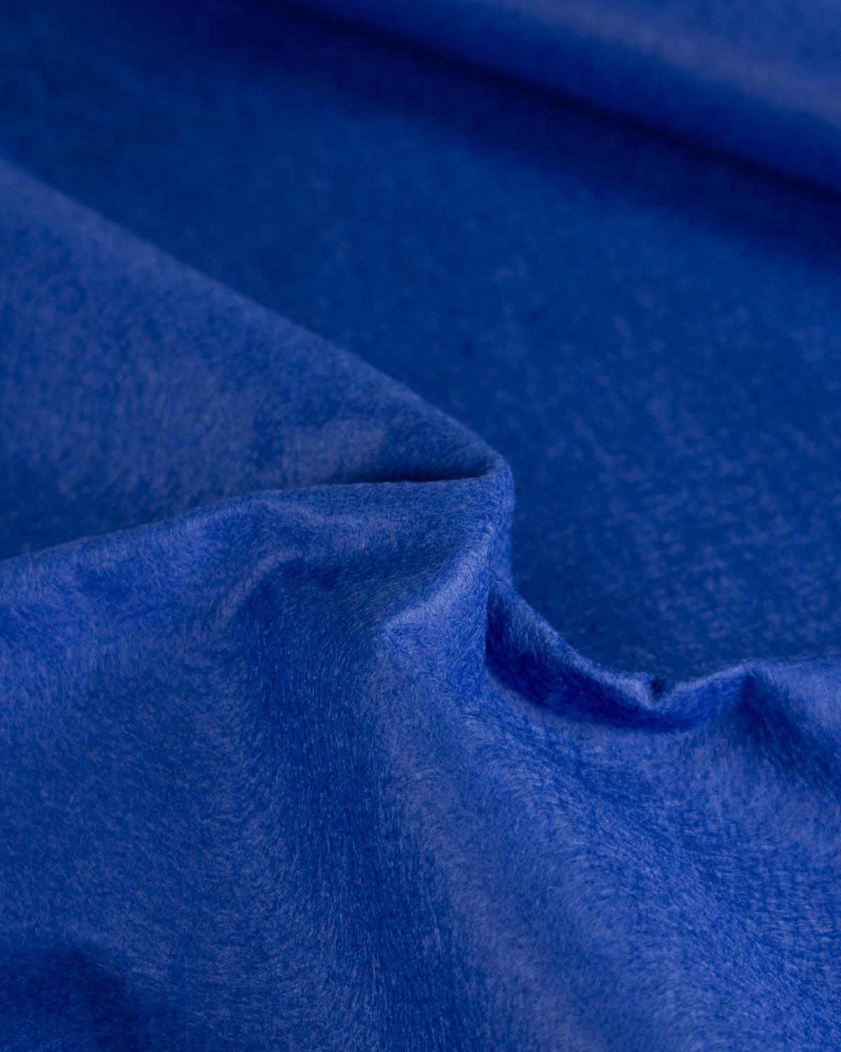 A close-up of draped royal blue wool and viscose felt fabric with a soft, plush texture.