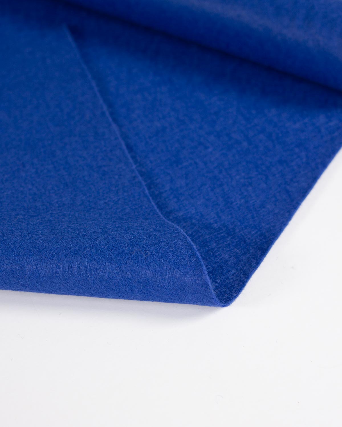 A close-up of folded royal blue wool and viscose felt fabric with a soft, brushed texture on a clean white background.