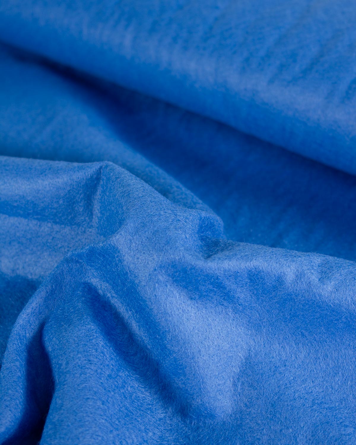 A close-up of draped royal blue wool and viscose felt fabric with a soft, velvety texture.