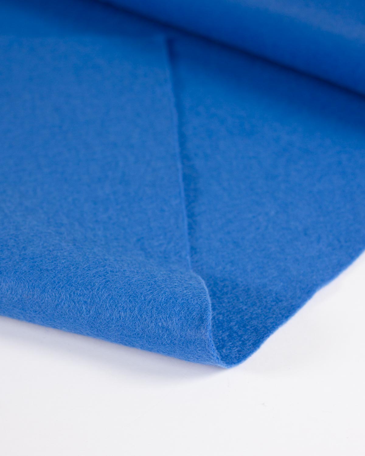 A close-up of a folded blue wool and viscose felt fabric showing its soft, textured surface on a clean white background.