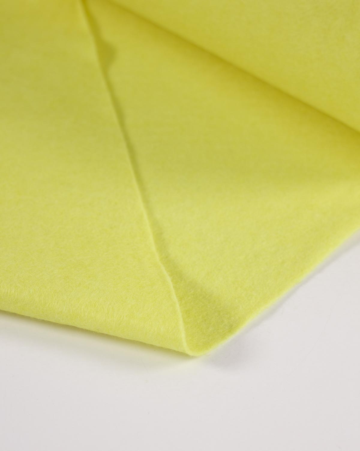 A close-up of folded bright lemon-yellow wool and viscose felt fabric on a plain white background.