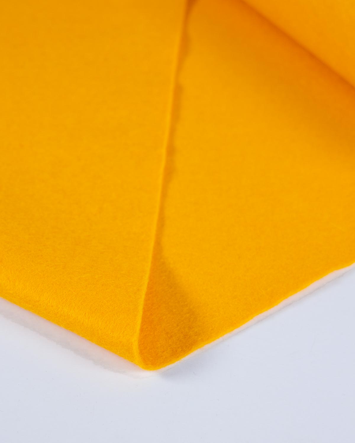 A piece of bright fiesta yellow wool and viscose felt fabric, folded on a plain white background to show its bold, even colour and texture. 