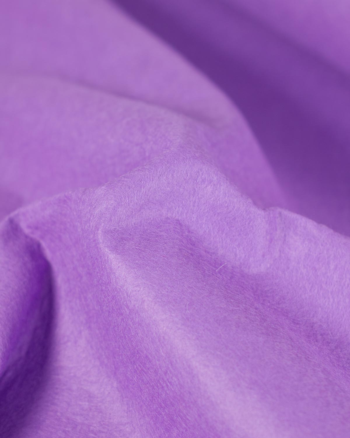 A close-up of draped lilac purple fabric with a soft, slightly fuzzy texture filling the frame, showcasing its firm structure. 