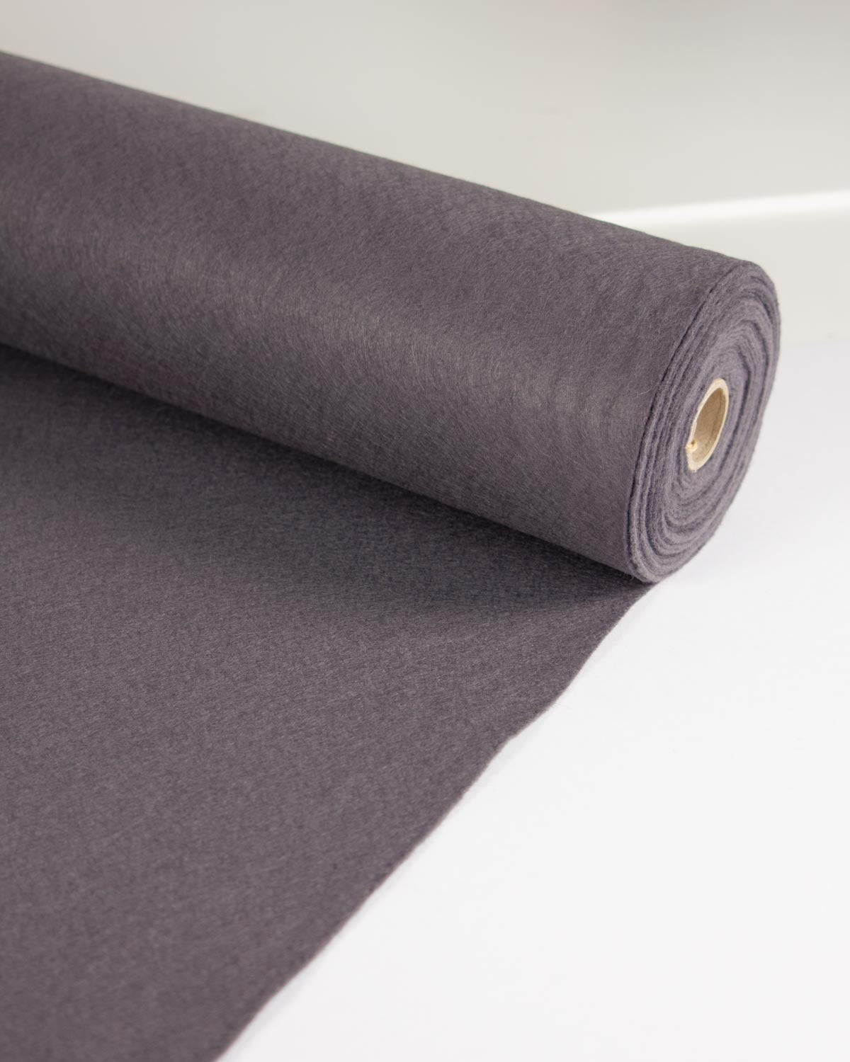 A roll of dark grey wool and viscose felt fabric, partially unrolled to show its texture, set against a clean white background.