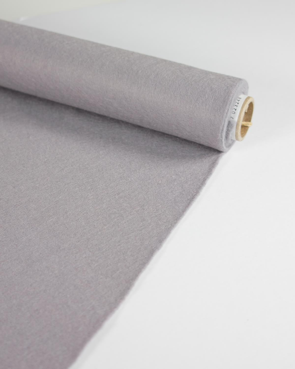 A roll of light grey wool and viscose felt fabric partially unrolled on a clean white surface, showing the texture of the material.