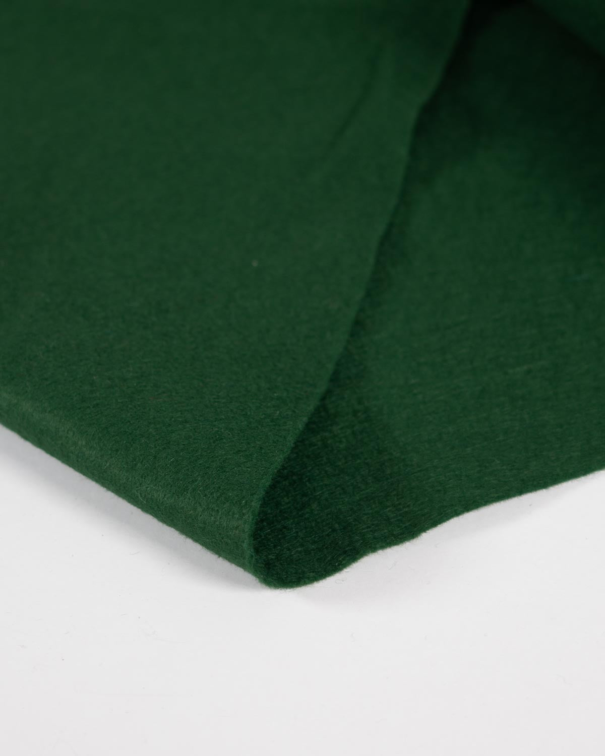 A close-up of a folded dark forest green wool and viscose felt fabric, showing its soft texture and matte finish against a clean white background.