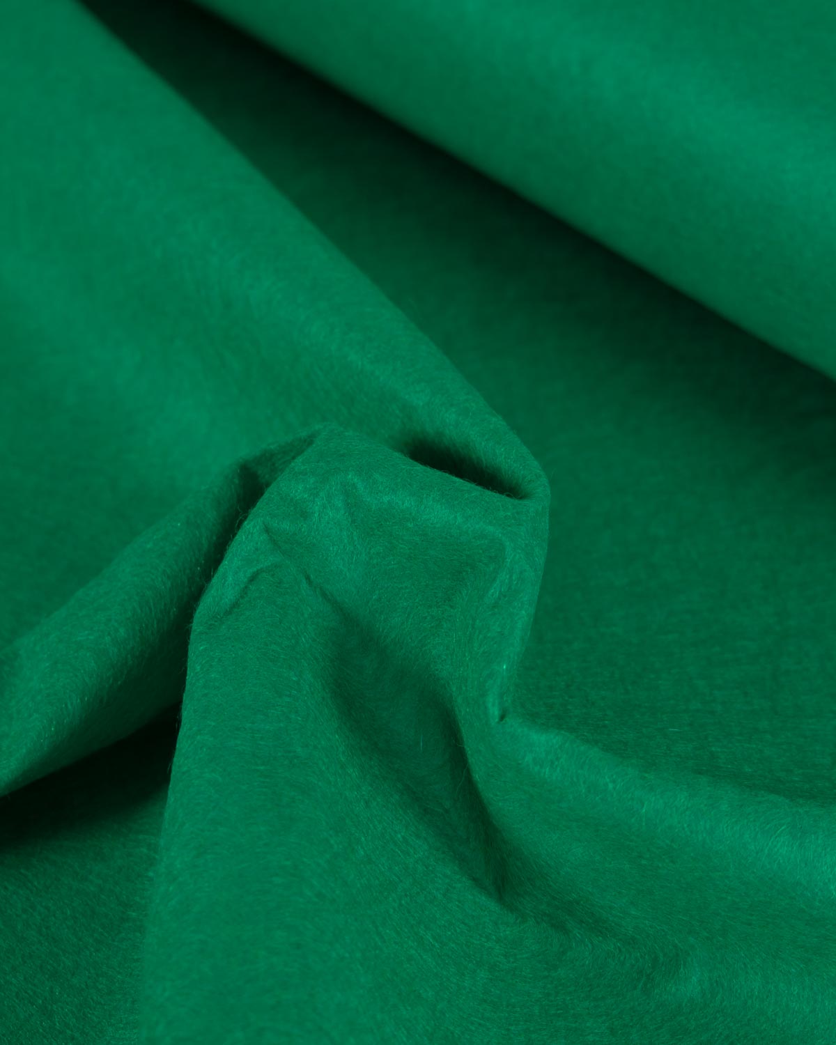 A close-up of scrunched jade green wool and viscose felt fabric with soft folds and a textured surface.