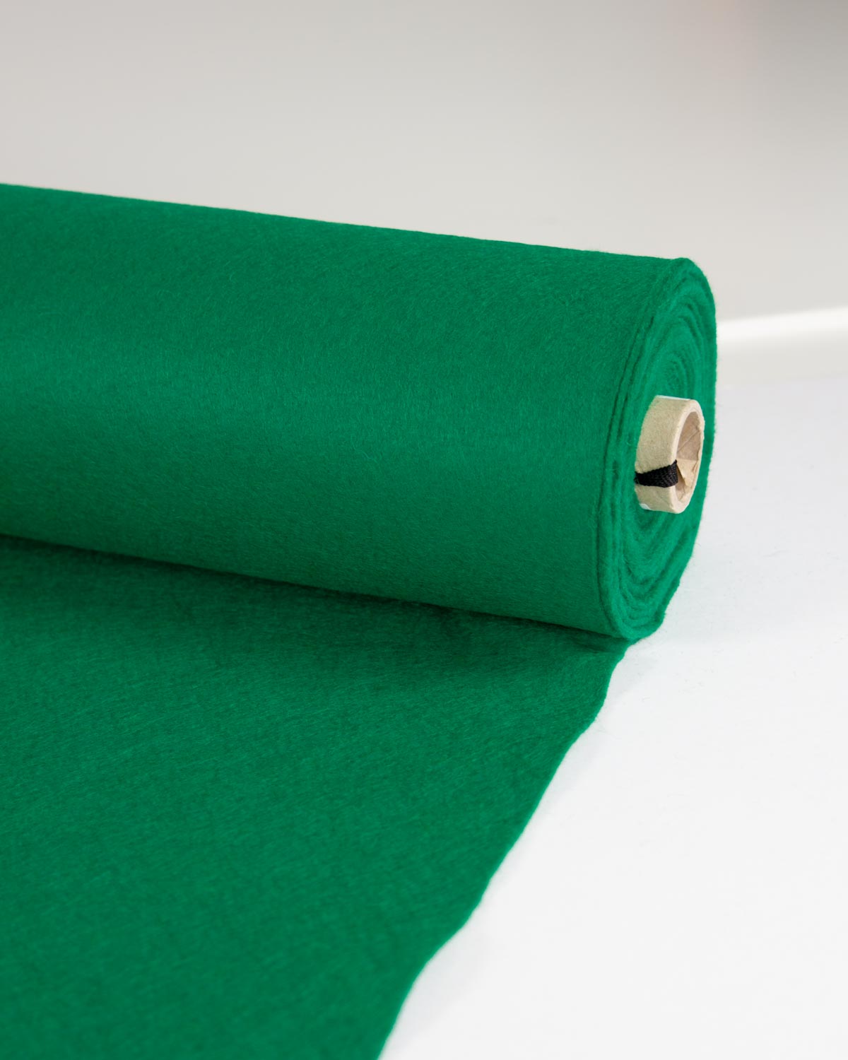A roll of vibrant jade green wool and viscose felt fabric, partially unrolled to show its soft, matte texture, set against a clean white background.