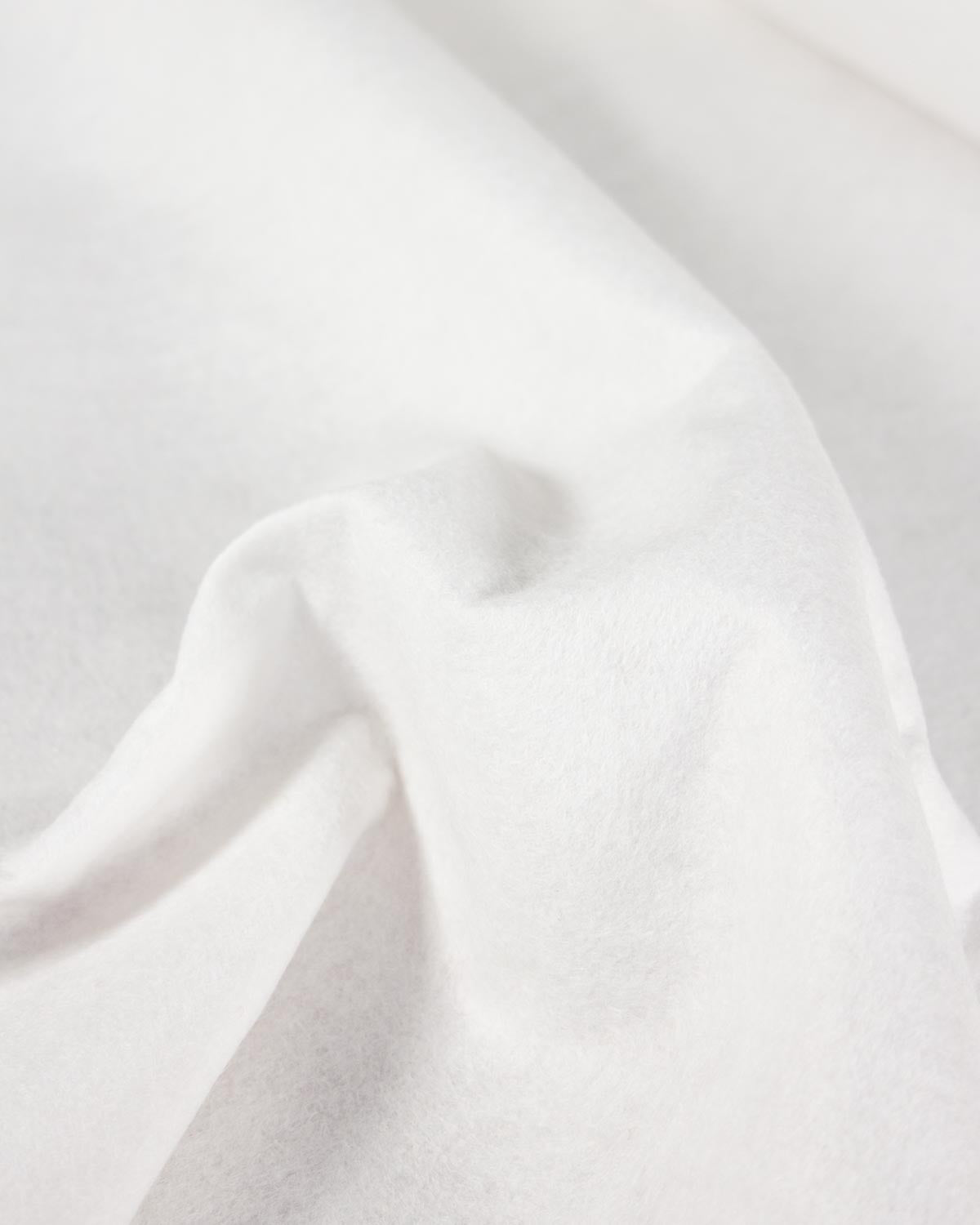 A close-up of draped white wool and viscose felt fabric with soft folds and a smooth texture.