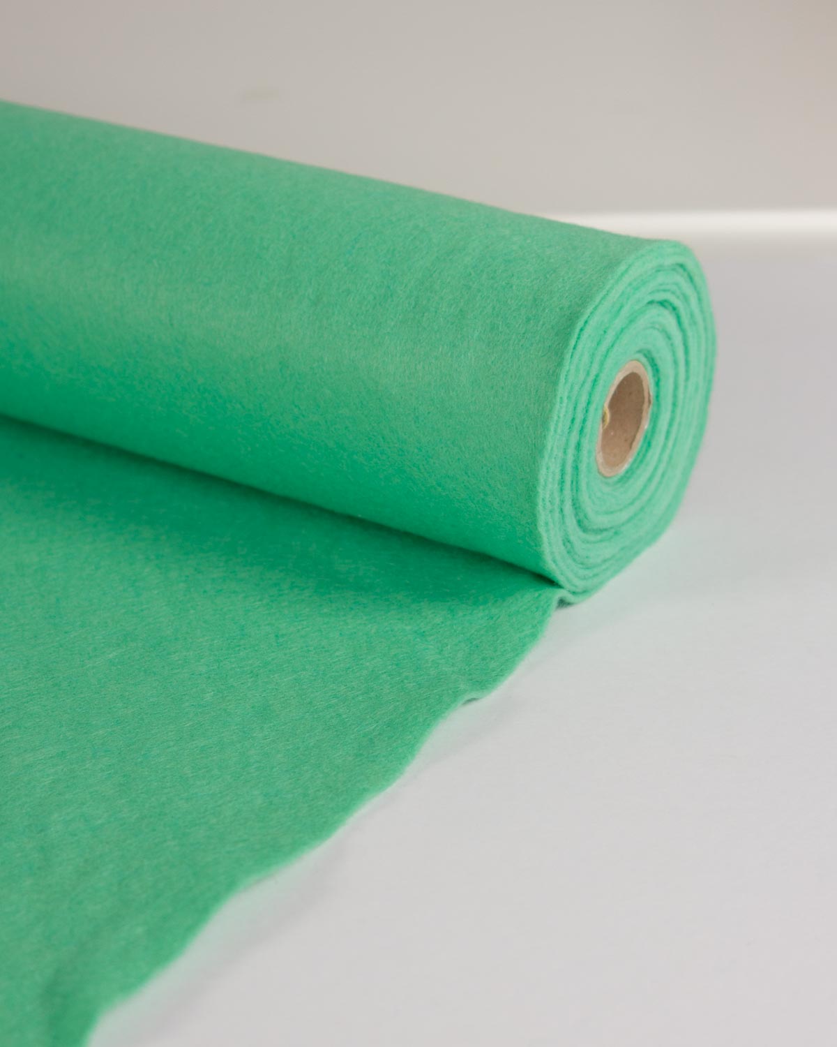 A roll of bright mint green wool and viscose felt fabric, partially unrolled, shown on a clean white background.