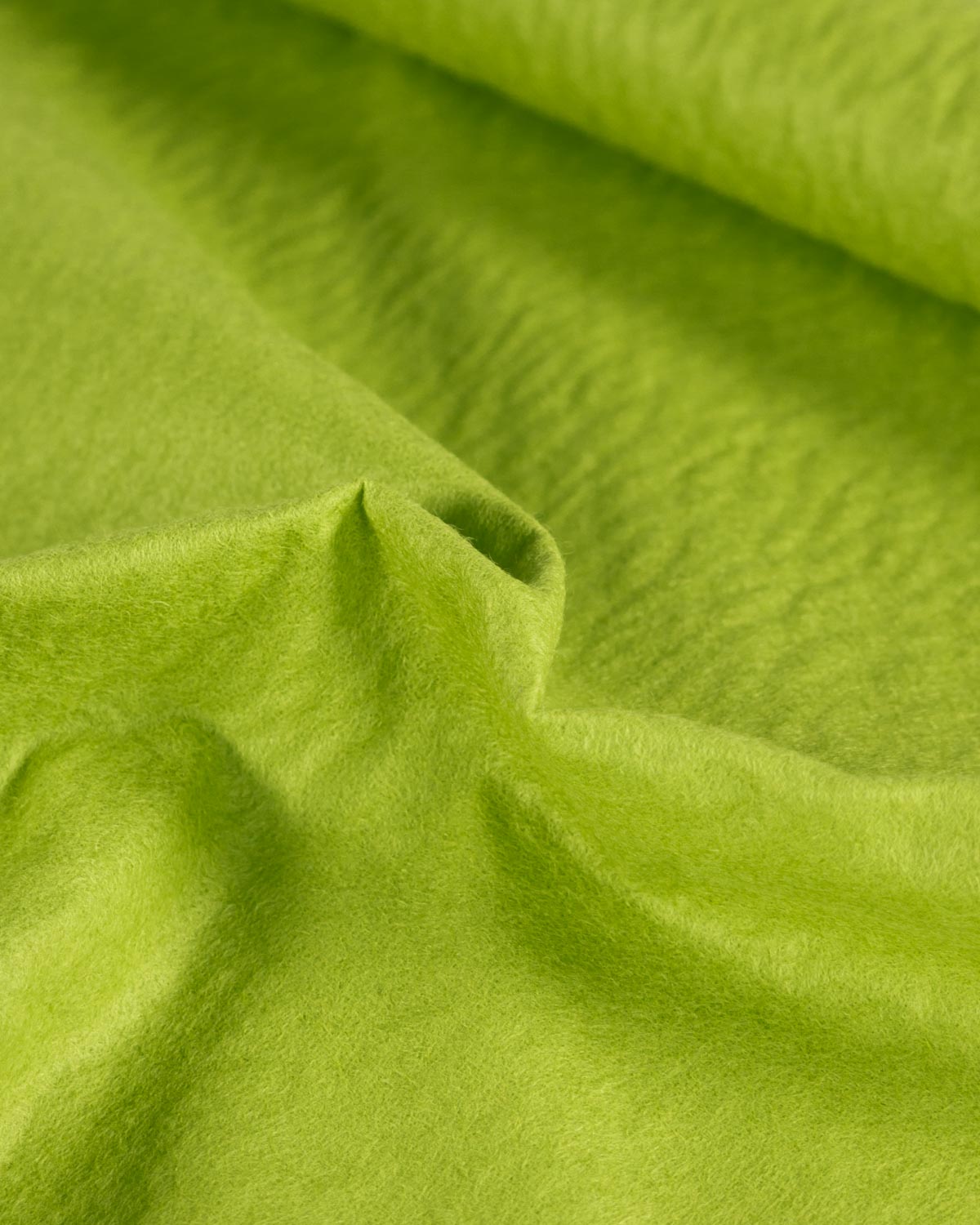 A close-up of draped leaf green wool and viscose felt fabric with a soft, textured surface.